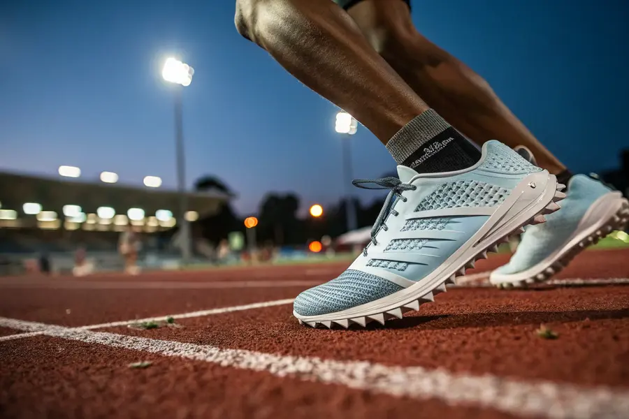 A runner wearing high-performance track shoes on a stadium track, illustrating the importance of proper footwear for both performance and injury prevention.